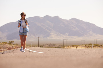 Woman On Vacation Hitchhiking Along Country Road