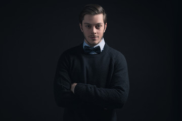 Man wearing dark blue sweater and light blue shirt with bow tie.