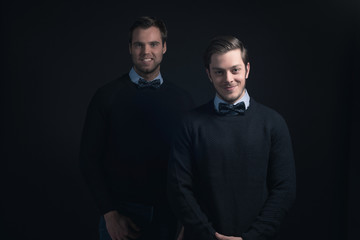 Obraz premium Two smiling men in dark blue sweater with shirt and bow tie.