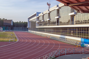 Беговые дорожки. Легкоатлетический стадион. Застекленное здание.