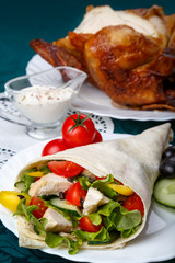 Shawarma on a white plate with a white sauce, doner kebab, traditional roll with meat and pita bread, selective focus on the filling