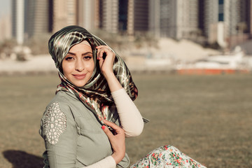 Fototapeta premium Smiling girl in hijab covering her eyes with happiness in Dubai Marina