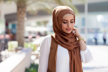 Smiling girl in hijab covering her eyes with happiness in Dubai Marina