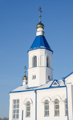 Fototapeta na wymiar The Church of St. Andrew/White bell tower of the Church of St. Andrew on a blue sky background