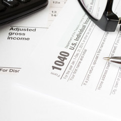 Close up U.S. Individual tax form 1040 with, glasses, calculator and pen.