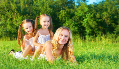 Fototapeta premium happy family mother and children twin sisters on meadow in summe