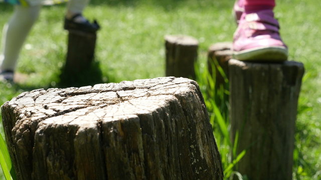 Children balancing on stumps in the nature