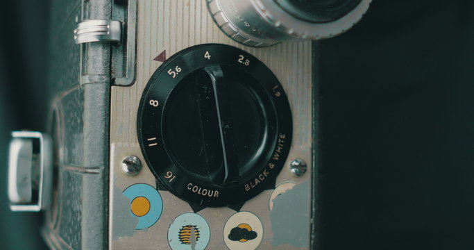 Adjusting the aperture value dial of a retro 8 mm film camera on tripod, ready for shooting.
