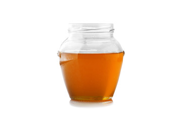 Glass jar of honey with wooden drizzler on a white