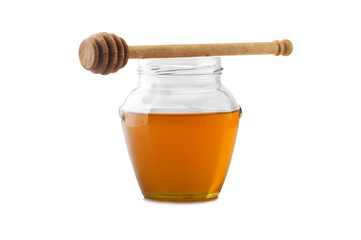 Glass jar of honey with wooden drizzler on a white