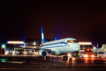 Airplane docked at the terminal and ready for takeoff. Modern international airport at night.