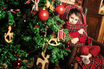 Family celebration of the New Year. Boy near a Christmas tree. Giving gifts. Holiday and fun.