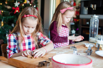 Little adorable girls baking gingerbread house on Christmas eve