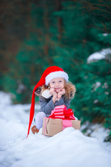 Little girl with Christmas box gift in winter outdoors on Xmas eve