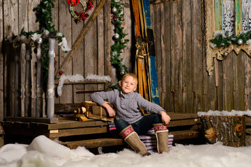 little boy in boots on background of the porch