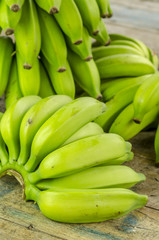 Bunch of green bananas on a wooden table.