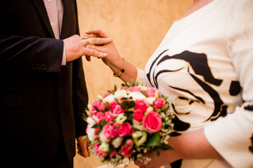 Obraz na płótnie Canvas Bride putting a wedding ring on groom's finger