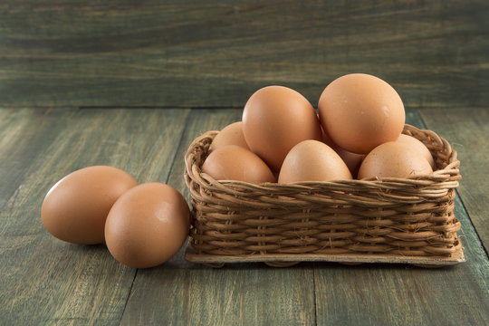 Huevos en canasta sobre mesa de madera.