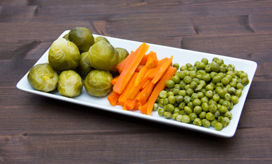 Tray with steamed vegetables on wooden table