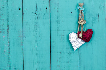 Skeleton key and hearts hanging on teal blue door
