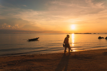 Tourists walk along the beach at sunset in koh Phangan, Thailand