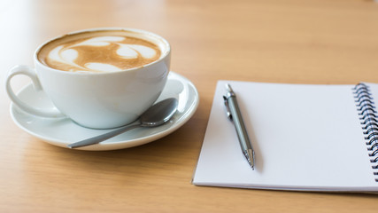 Coffee cup and notebook on grunge wooden background