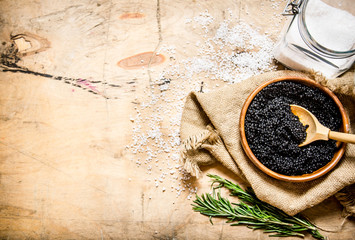The concept of black caviar. Black caviar in cup with salt and rosemary.