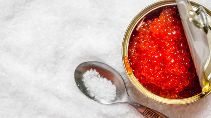 Jar with red caviar and spoon of salt.