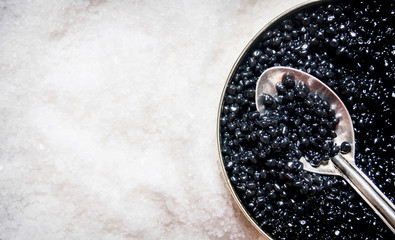 Jar with black caviar and spoon of salt.