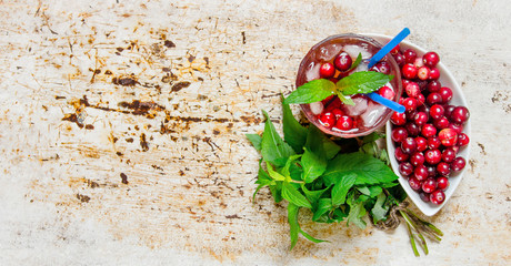 Berry cocktail in glass with ice and mint on old table.  Free space for text.