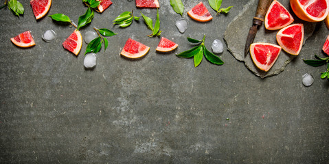 Pieces of sliced grapefruit with leaves and ice.