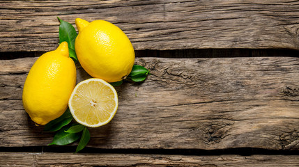 Lemons with leaves. On wooden background.