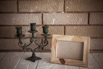 Photo frame and candlestick on wooden table over wall background