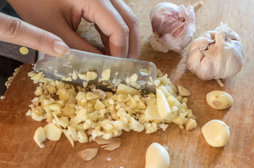 Chef slicing garlic  on the cutting board with a knife