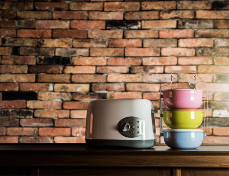 Colorful tiffin carrier and toaster on wooden cupboard