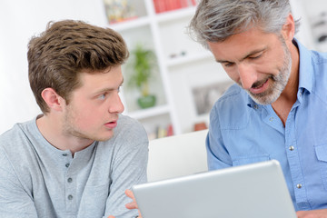Two men looking at tablet computer - obrazy, fototapety, plakaty