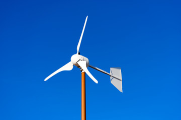 Small Wind Turbine on Blue Sky / Close up of a small wind turbine with blades on clear blue sky © Alberto Masnovo