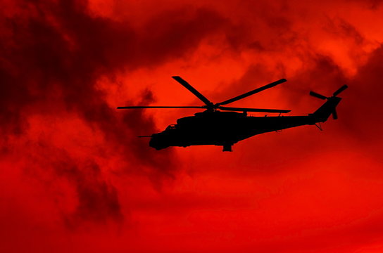 Military helicopter on a background of red sky