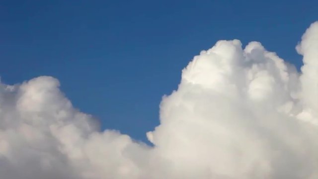 Stream of lumpy puffy sunny clouds on deep blue sky background. Meditative view of calm and relaxing motion of white steam river. Upper edge of sunlit cloud sea.