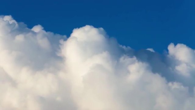 River of lumpy puffy sunny clouds on deep blue sky background. Meditative view of calm and relaxing motion of white steam stream. Upper edge of sunlit cloud sea.