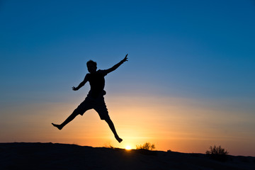 Fototapeta na wymiar Silhouette of a boy jumping in the sun
