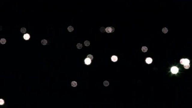 A group of sun specks on dark background. Water reflection of sun beams out of focus. Play of sunshine on lake ripple. Meditative intro with sparkling gleams in full HD footage with 1080p.