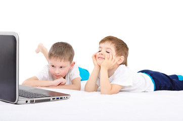Two boys looking on laptop lying in bed