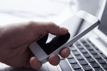 Person using phone while working on a Laptop
