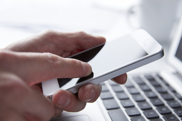 Person using phone while working on a Laptop 