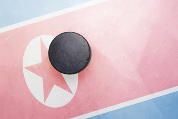 old hockey puck is on the ice with north korea flag