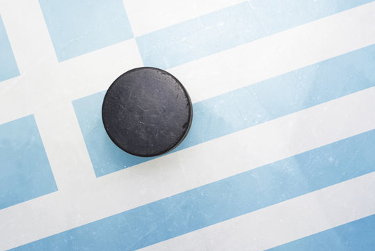old hockey puck is on the ice with greece flag