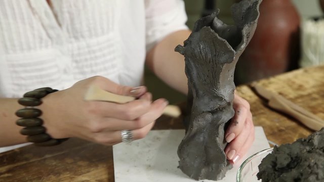 Sculptor woman shaping clay sculpture with hands close-up
