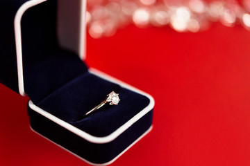 stylish luxury ring with diamond in blue box on red background,