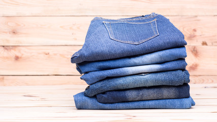 Piles of jeans on wooden background